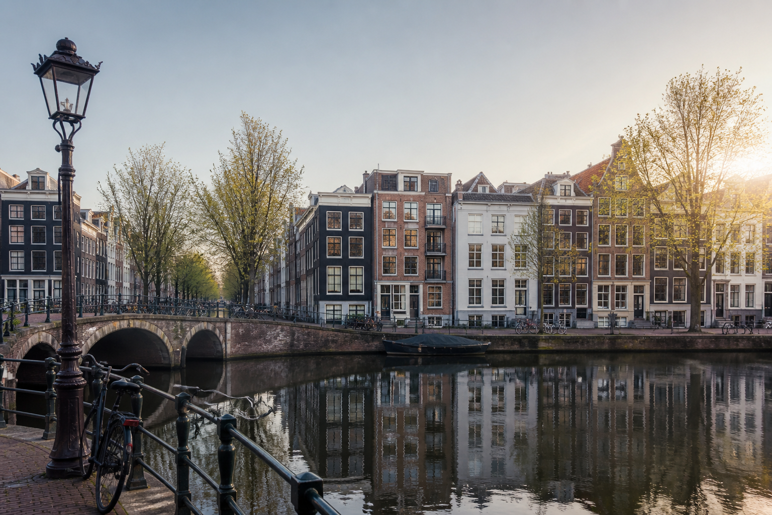 Amsterdamse gracht met smalle huizen, brug en weerspiegeling in het water